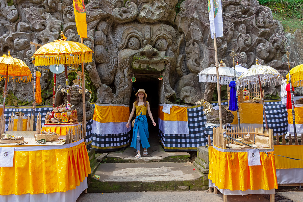 a tourist in a sarong standing close to the entrance of Goa Gajah