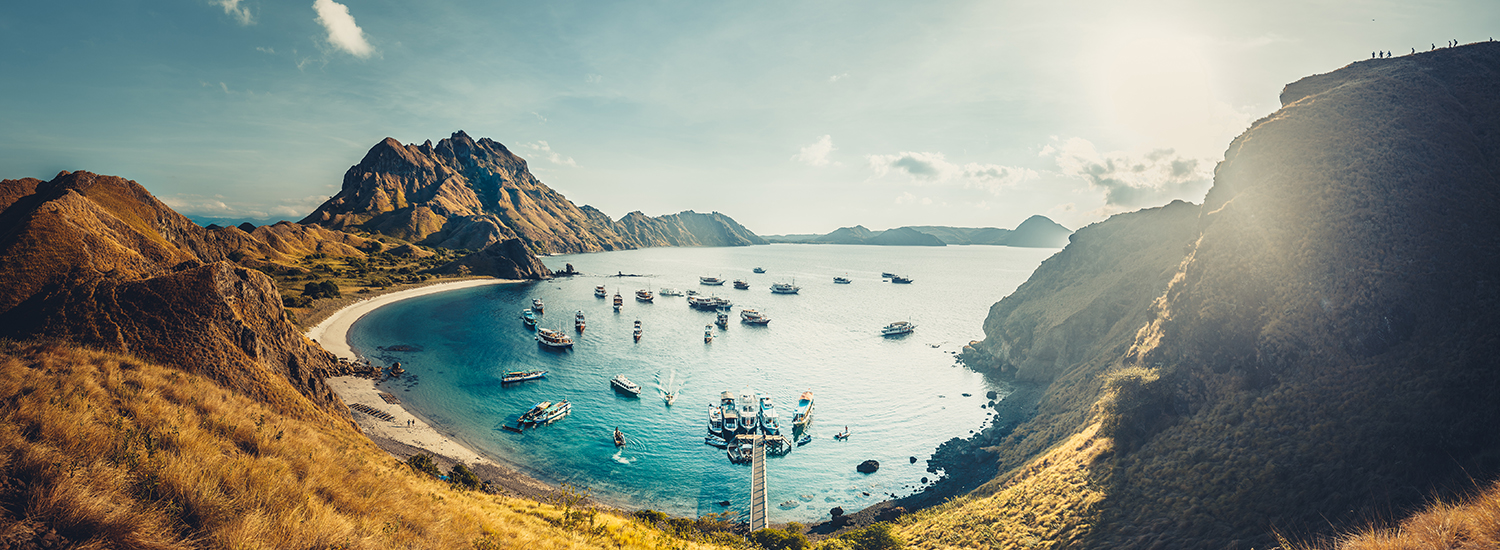 Tourists arriving by boat at Padar Island Beach with stunning cliffs in view