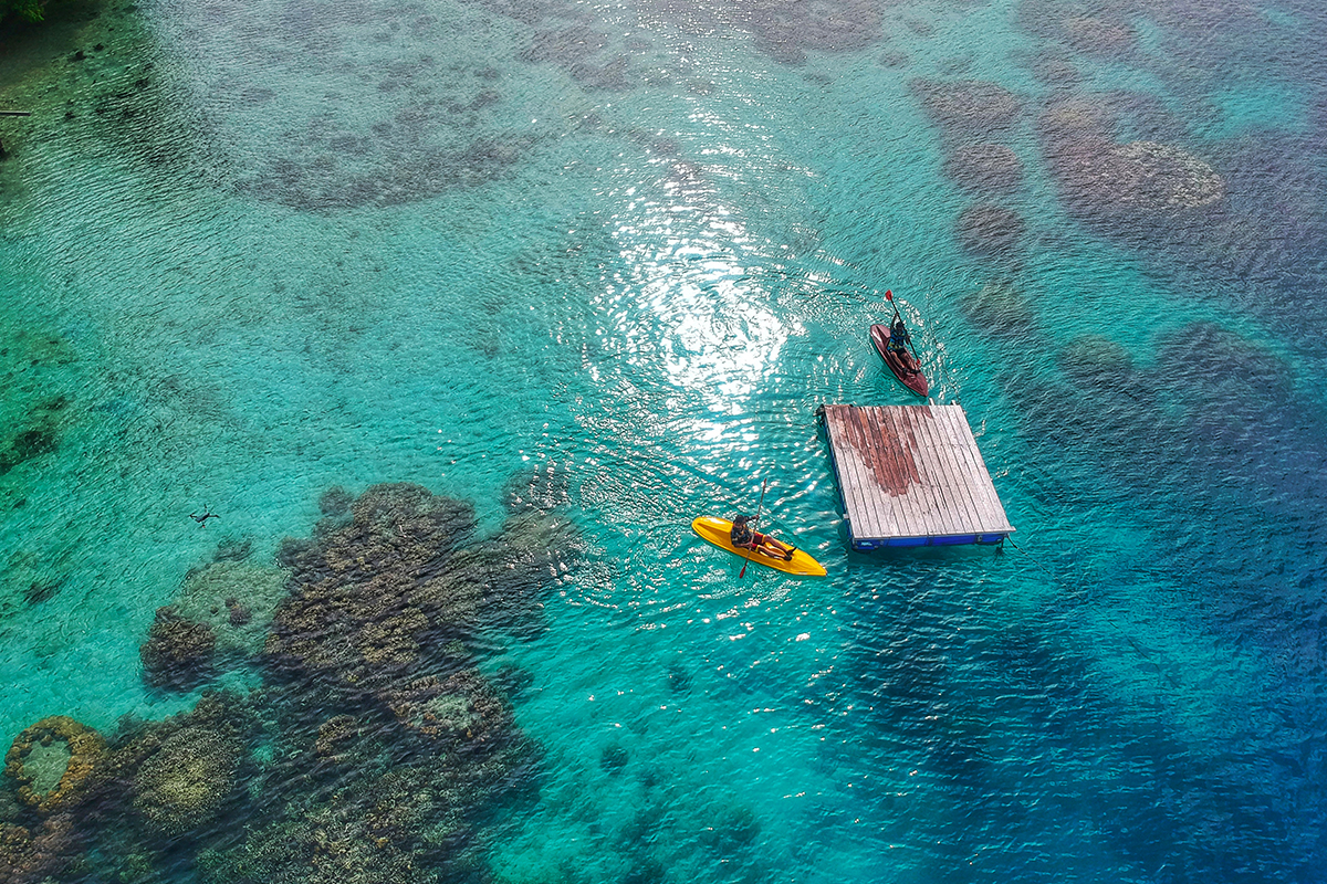 Wisatawan yang sedang menaiki perahu kayak di laut lepas