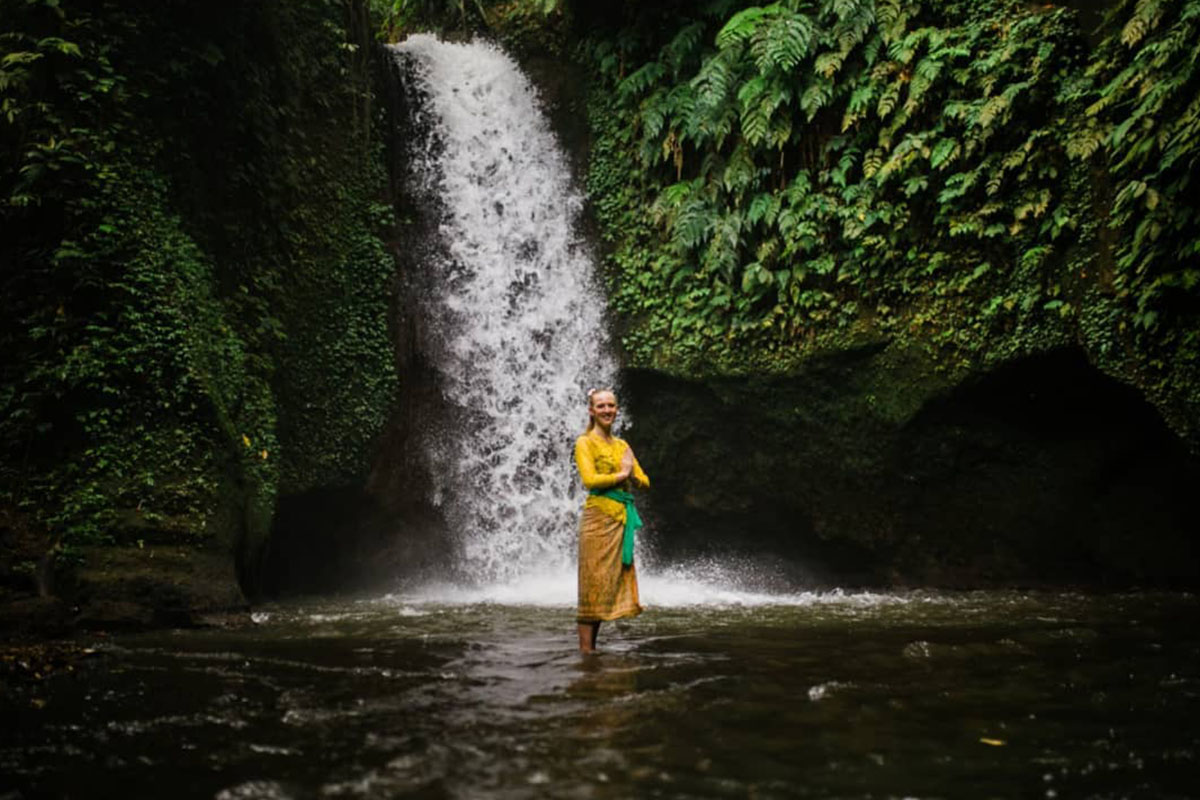 a girl standing near Manuaba Waterfall