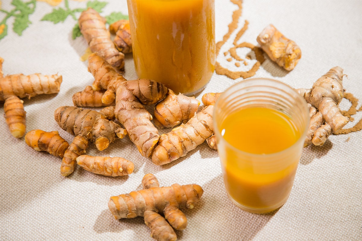 cups of jamu kunyit asam and turmeric roots