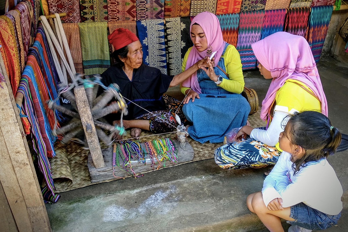 tourists approaching a lady weaving in Sade Village