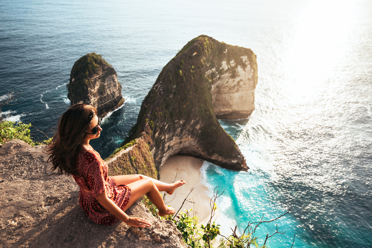 a woman sitting to view the stunning Kelingking Beach Bali