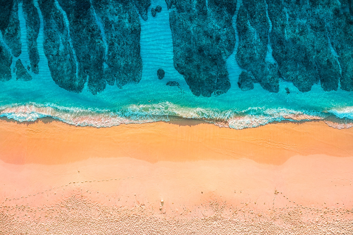 Pantai pasir putih dengan ganggang dan air laut biru