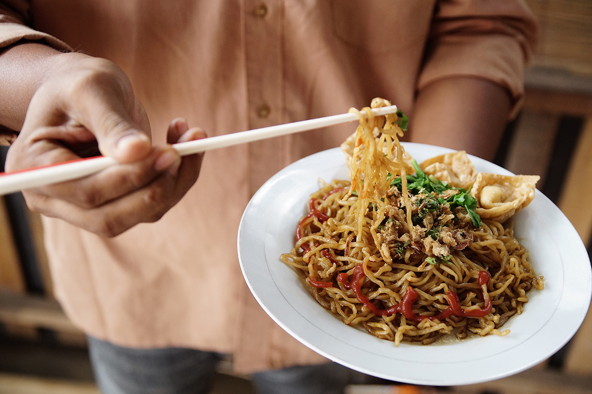 sepiring bakmi yang dipegang oleh seseorang