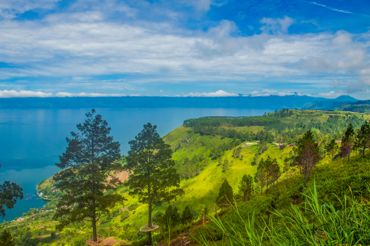 bukit simarjarunjung yang hijau dengan air laut yang biru