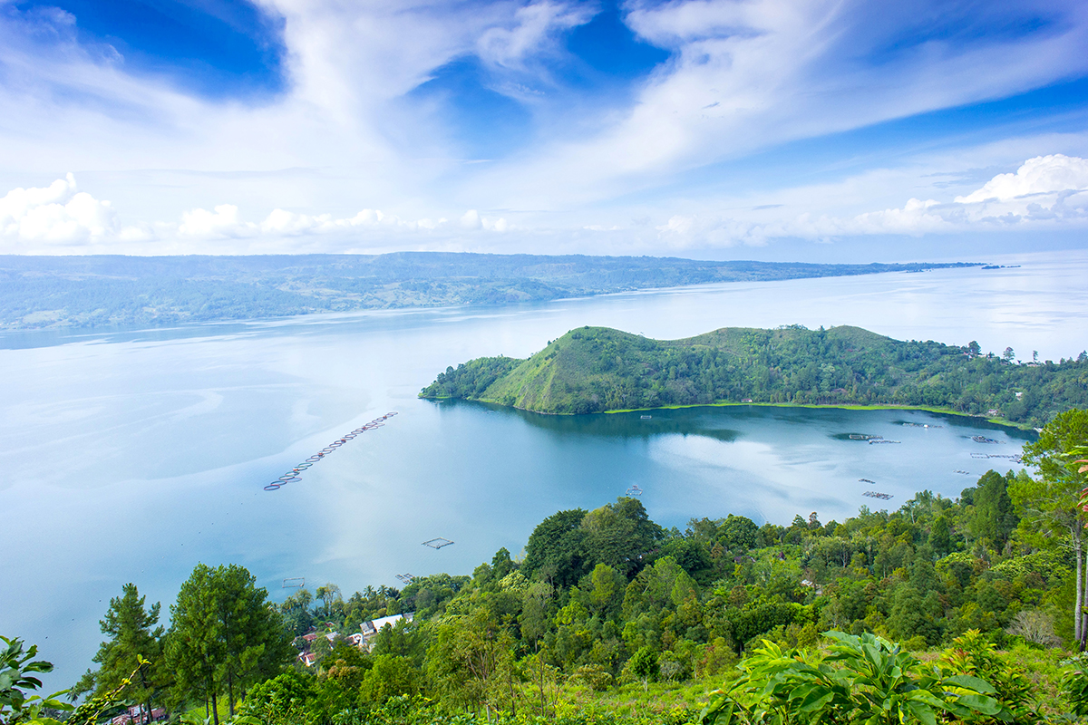 Lake Toba in North Sumatra, vast open lake, lush forest, stretching hills, blue sky