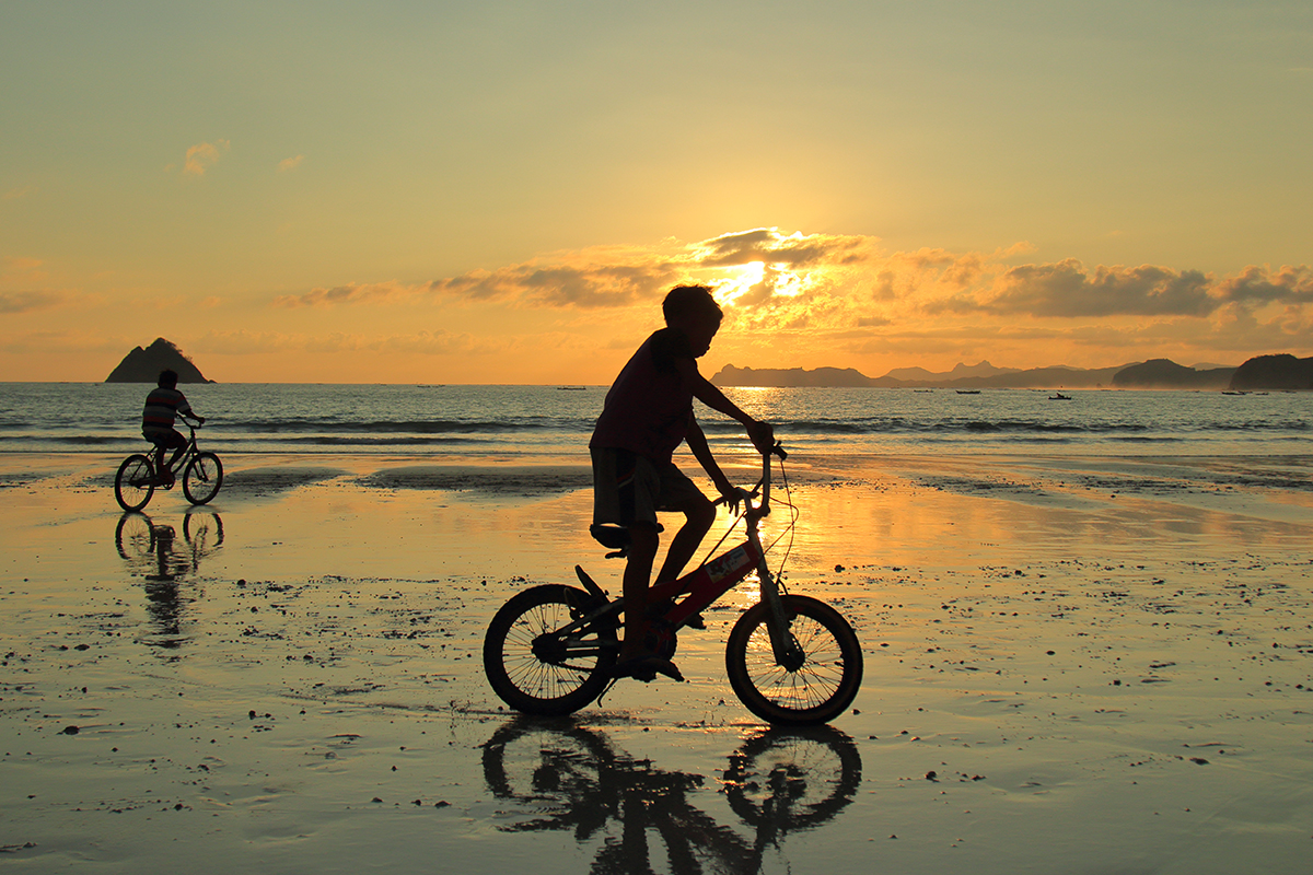 Potret turis yang sedang bersepeda di tepi pantai