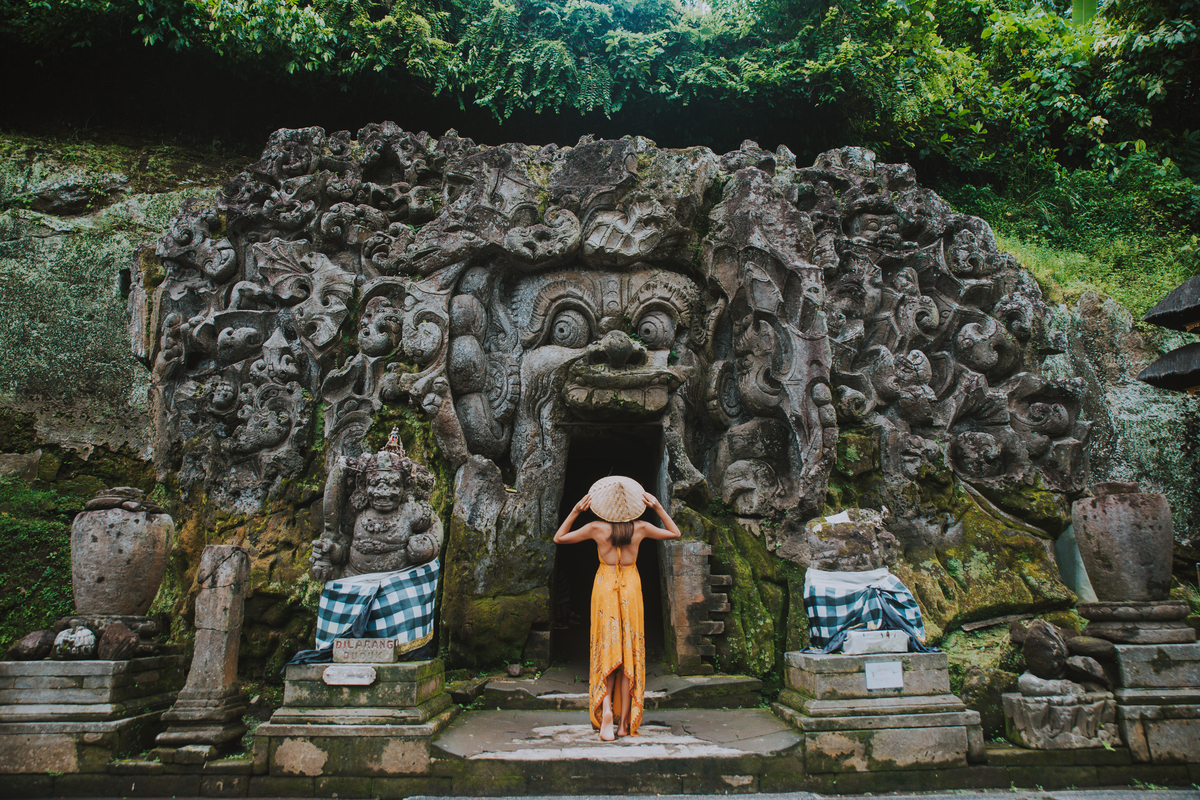 a female foreigner exploring Goa Gajah in Gianyar, Bali, serves as an archaeological place, traditional architecture with statues and stupas
