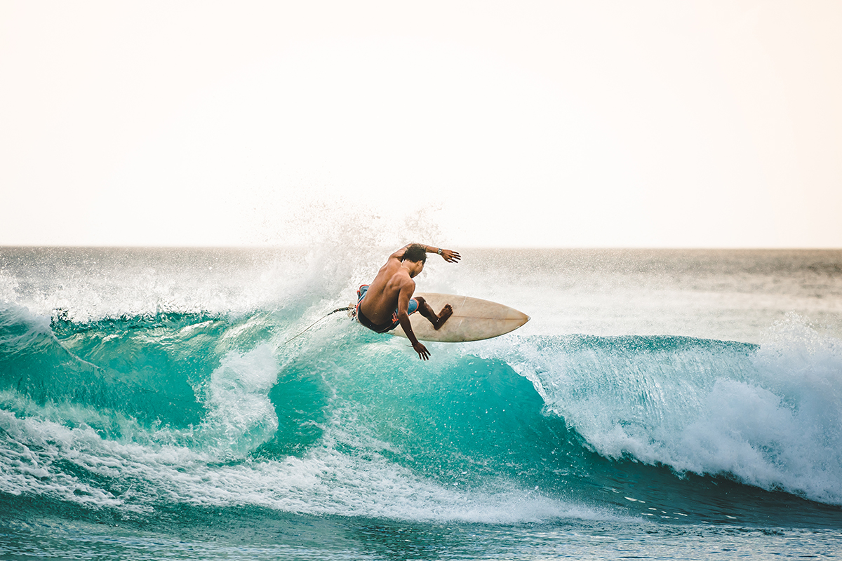 Seorang pria sedang berselancar keren di pantai Bali